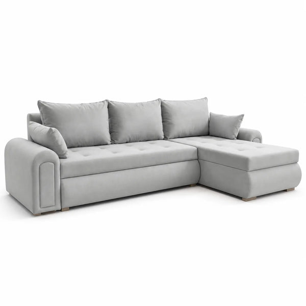 A light gray upholstered sectional sofa with a right-facing chaise ottoman, multiple matching back cushions, and tufted seat detailing, shown on a plain white studio background.