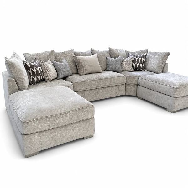 A light gray upholstered sectional sofa with a chaise on the left and a matching ottoman on the right, styled with multiple gray, beige, and black-and-white patterned throw pillows on a clean white background.