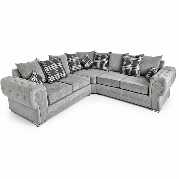 A gray upholstered sectional sofa with rolled arms, tufted front panels, and multiple plaid throw pillows, shown on a plain white studio background.